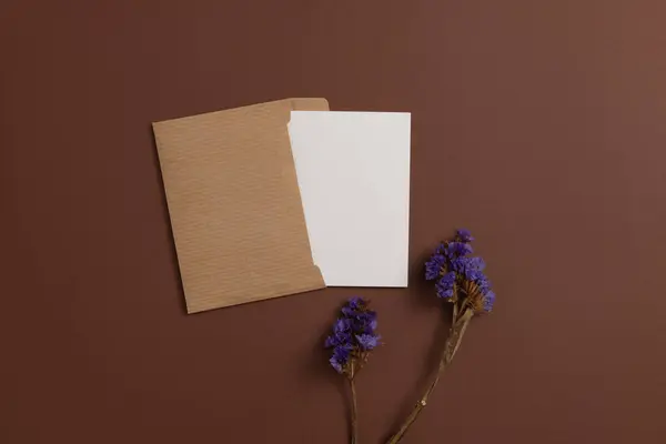 Mockup of a card made from eco-friendly materials and decorated with a composition of dried blue flowers on a brown background