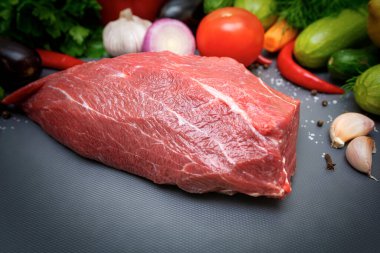 Sebze arka planında kesme tahtasındaki bir parça et..