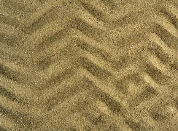 stock image The wave pattern is drawn on the sea sand.