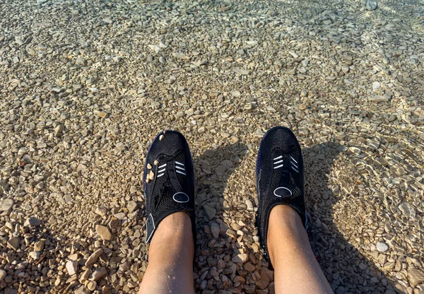 在有石头和危险底部的地方游泳用的鞋子 图库照片