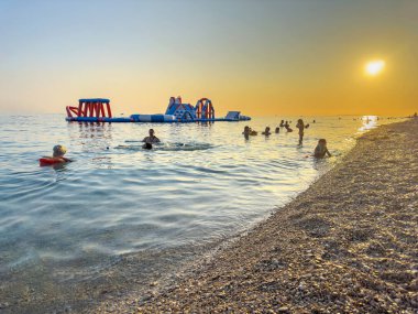 PRIMOSTEN, CROATIA - 27 Temmuz 2023: İnsanlar Primosten kasabasının günbatımında yıkanır.