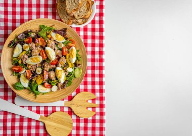 Sebze salatası ve kareli masa örtüsü. Karıştırmak için özel aygıtlar var.