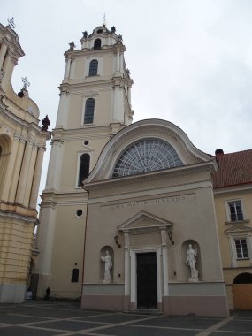 Sağda Alma Mater Vilnensis, Vilnius, Litvanya 'nın bir binası var. Arka planda St. John Kilisesi' nin çan kulesi.