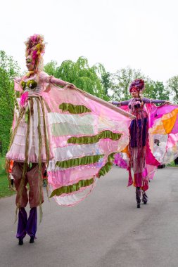 Garden Keukenhof, Lisse, NETHERLANDS, 15 Haziran 2024. Çiçek gösterisi, çiçekleri sembolize eden elbiseler giymiş ayaklıklarla yürüyen genç kadınlar..