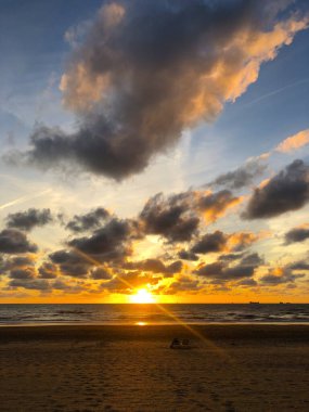 Kuzey sahilinde gün batımı, Scheveningen, Lahey, Hollanda. Bulutlu Mavi Gökyüzü ve Güneş Işığı