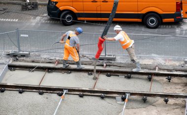 Laan van Nieuwe Oost-Indie, Lahey, Hollanda - 20 Ağustos 2024; Turuncu tulumlu çok sayıda yol işçisi tramvay raylarını onarıp yeni beton döker