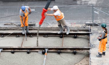 Laan van Nieuwe Oost-Indie, Lahey, Hollanda - 20 Ağustos 2024; Turuncu tulumlu çok sayıda yol işçisi tramvay raylarını onarıp yeni beton döker