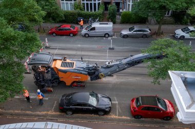 Laan van Nieuwe Oost-Indie, Lahey, Hollanda - 20 Ağustos 2024; Turuncu yelekli işçi ve yöneticilerden oluşan bir ekip zayıf asfaltı denetliyor ve yol çalışmaları hazırlıyor.