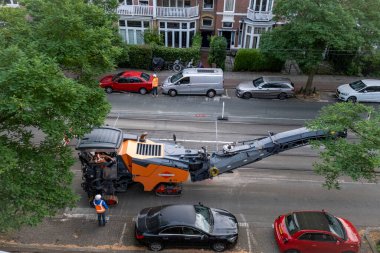 Laan van Nieuwe Oost-Indie, Lahey, Hollanda - 20 Ağustos 2024; Turuncu yelekli işçi ve yöneticilerden oluşan bir ekip zayıf asfaltı denetliyor ve yol çalışmaları hazırlıyor.