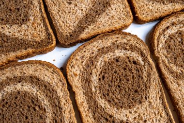 Dilimlenmiş koyu ve hafif ekmek hamuru beyaz arka planda bükülmüş spiral şeklinde öğütülmüş.