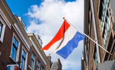 Mavi gökyüzü arka planında Hollanda bayrağı ve eski Hollands binası olan eski şehir merkezi.
