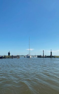 Üç. Volendam, Hollanda - 30 Haziran 2025: Hollanda 'nın Kuzey Hollanda eyaletindeki Volendam antik köyünün önünde güzel beyaz bir yat denize açıldı