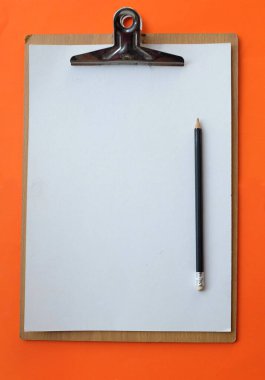 Düz uzanış, üst görünüm ofis masa çalışma alanı beyaz kağıt kağıtlı pano ve turuncu arka planda kalem izolasyonu. İş konsepti ve ofis malzemeleri 