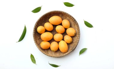 Beyaz zemin üzerinde izole edilmiş bambu bir sepetin içinde taze taze, olgun Marian eriği, Tayland meyvesi yığını yatıyordu (mayongchid maprang marian erik ve erik mango, thailand). Thailan 'ın sağlıklı meyveleri