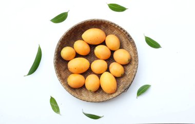 Beyaz zemin üzerinde izole edilmiş bambu bir sepetin içinde taze taze, olgun Marian eriği, Tayland meyvesi yığını yatıyordu (mayongchid maprang marian erik ve erik mango, thailand). Thailan 'ın sağlıklı meyveleri