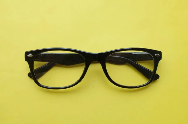 閉じてフラットは 明るい黄色の背景の上に男性と女性のための現代的なメガネ アイウェア 黒いフレームのファッションを置きます — ストック写真