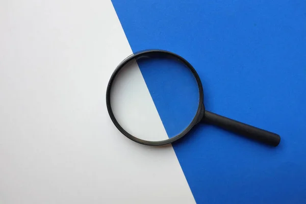 black frame a magnifying glass on Rectangle shape colored paper white and blue background