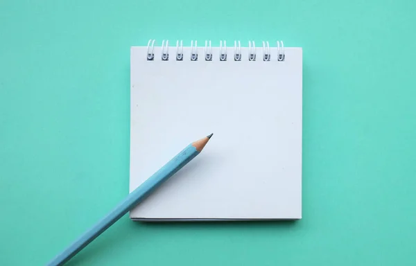 Stock image close up and flat lay a pencil on white spiral notepad on a table green pastel background. education and business concept.school supplies and office work