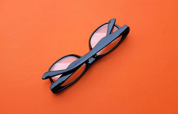 在橙色的背景下明亮的隔离带上 有一副现代的眼镜 黑色镜框供男人和女人穿 — 图库照片