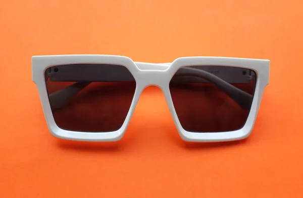 sunglasses in white plastic frame isolated on orange .Retro fashion bold frame style.