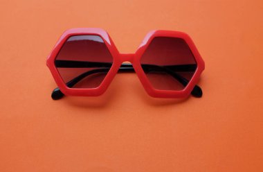 Mavi beşgen şeklindeki güneş gözlüklerini kapat. Turuncu bir arkaplanda izole et.