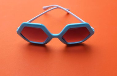 Mavi beşgen şeklindeki güneş gözlüklerini kapat. Bir portakala izole et.