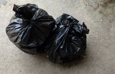 Beton zeminde izole edilmiş siyah çöp torbaları. Atık yönetimi ve çevrenin sembolü.