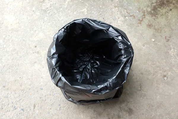 将黑色塑料袋隔离在水泥地面上的垃圾桶 废物管理和环境的象征 — 图库照片