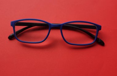 Modern bir gözlük, gözlük, gözlük, gözlük, gözlük, mavi çerçeveler, kırmızı arka planda oturan erkekler ve kadınlar için modadır.