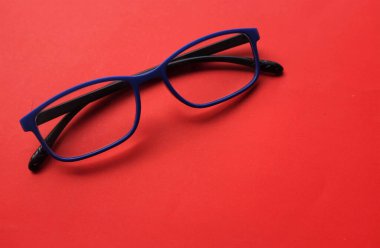 Modern bir gözlük, gözlük, gözlük, gözlük, gözlük, mavi çerçeveler, kırmızı arka planda oturan erkekler ve kadınlar için modadır.