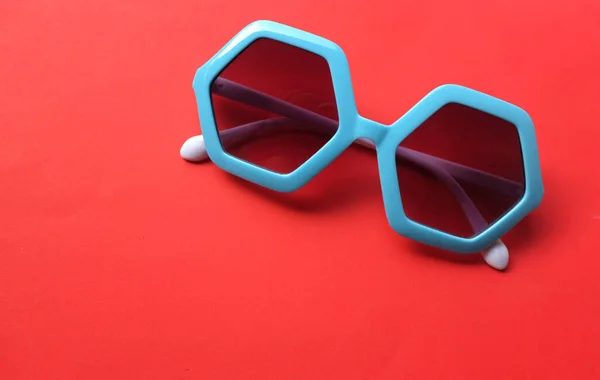 Fechar Azul Pentágono Forma Óculos Sol Isolar Fundo Vermelho — Fotografia de Stock