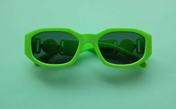 绿色塑料相框的太阳镜 隔离在绿色粉刷的背景上 复古时尚大胆的相框风格 — 图库照片