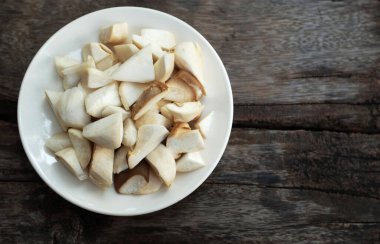 Dilimlenmiş çiğ kral istiridye mantarı ve rosmary (Pleurotus eryngii) tahtadan bir arka planda izole edilmiş beyaz bir tabakta, yemek hazırlayın.