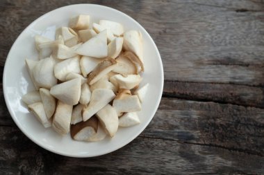 Dilimlenmiş çiğ kral istiridye mantarı ve rosmary (Pleurotus eryngii) tahtadan bir arka planda izole edilmiş beyaz bir tabakta, yemek hazırlayın.