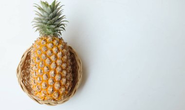 taze bir ananas (ananas comosus (l.) merr) olgun sarı organik bir sepetin içinde beyaz bir zemin üzerinde izole edilmiş. yaz meyveleri konsepti.