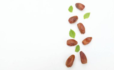 Lezzetli kuru hurma yığınları ya da palmiye ağaçları ya da yeşil yapraklı palmiye ağaçları beyaz bir arka planda izole edilir. Atıştırmalık sağlıklı, Arap yemeği, tropikal meyve