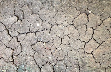 Kuru çatlamış toprak dokusu ve çatlak kahverengi çamur yüzeyi. Zemin, kuraklık ve ölüm kavramına sahip arka plan veya grafik tasarımı için üst görüntüde çatlaklar var. yatay resim
