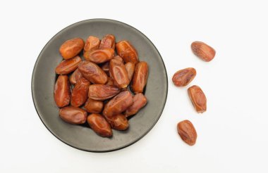 Lezzetli kuru hurma yığınları ya da palmiye ağaçları ya da palmiye anka kuşu dactylifera meyveli siyah seramik plato beyaz arka planda. Atıştırmalık sağlıklı, Arap yemeği, tropikal meyve