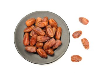 Lezzetli kuru hurma yığınları ya da palmiye ağaçları ya da palmiye anka kuşu dactylifera meyveli siyah seramik plato beyaz arka planda. Atıştırmalık sağlıklı, Arap yemeği, tropikal meyve