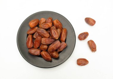 Lezzetli kuru hurma yığınları ya da palmiye ağaçları ya da palmiye anka kuşu dactylifera meyveli siyah seramik plato beyaz arka planda. Atıştırmalık sağlıklı, Arap yemeği, tropikal meyve