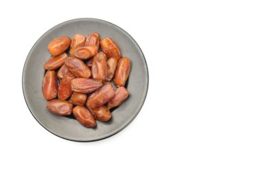 Lezzetli kuru hurma yığınları ya da palmiye ağaçları ya da palmiye anka kuşu dactylifera meyveli siyah seramik plato beyaz arka planda. Atıştırmalık sağlıklı, Arap yemeği, tropikal meyve