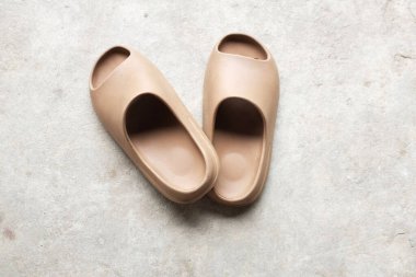 Çimento zeminine izole edilmiş, açık ayak parmağı yastıklı bir çift slayt. Kadın modası. Kadın yaz ayakkabıları, yumuşak terlikler.