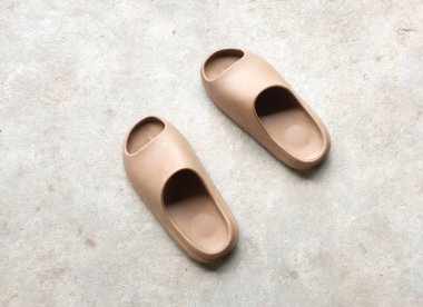 Çimento zeminine izole edilmiş, açık ayak parmağı yastıklı bir çift slayt. Kadın modası. Kadın yaz ayakkabıları, yumuşak terlikler.