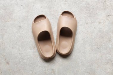 Çimento zeminine izole edilmiş, açık ayak parmağı yastıklı bir çift slayt. Kadın modası. Kadın yaz ayakkabıları, yumuşak terlikler.