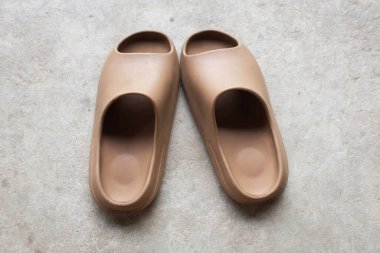 Çimento zeminine izole edilmiş, açık ayak parmağı yastıklı bir çift slayt. Kadın modası. Kadın yaz ayakkabıları, yumuşak terlikler.