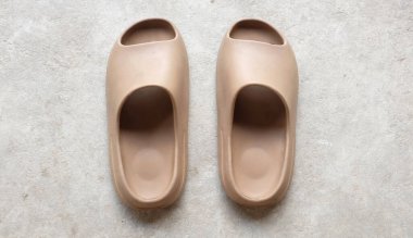 Çimento zeminine izole edilmiş, açık ayak parmağı yastıklı bir çift slayt. Kadın modası. Kadın yaz ayakkabıları, yumuşak terlikler.