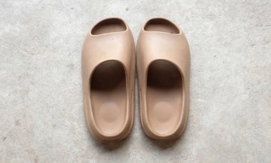 Çimento zeminine izole edilmiş, açık ayak parmağı yastıklı bir çift slayt. Kadın modası. Kadın yaz ayakkabıları, yumuşak terlikler.