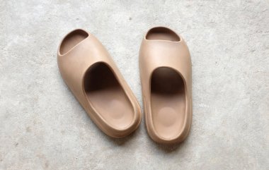 Çimento zeminine izole edilmiş, açık ayak parmağı yastıklı bir çift slayt. Kadın modası. Kadın yaz ayakkabıları, yumuşak terlikler.