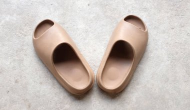 Çimento zeminine izole edilmiş, açık ayak parmağı yastıklı bir çift slayt. Kadın modası. Kadın yaz ayakkabıları, yumuşak terlikler.