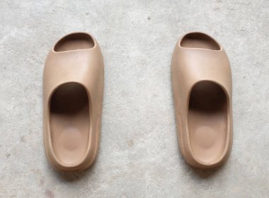 Çimento zeminine izole edilmiş, açık ayak parmağı yastıklı bir çift slayt. Kadın modası. Kadın yaz ayakkabıları, yumuşak terlikler.